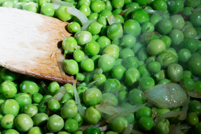 Close-up of spatula on green peas cooking in pan