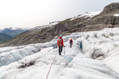 Rear view of people hiking on mountain during winter