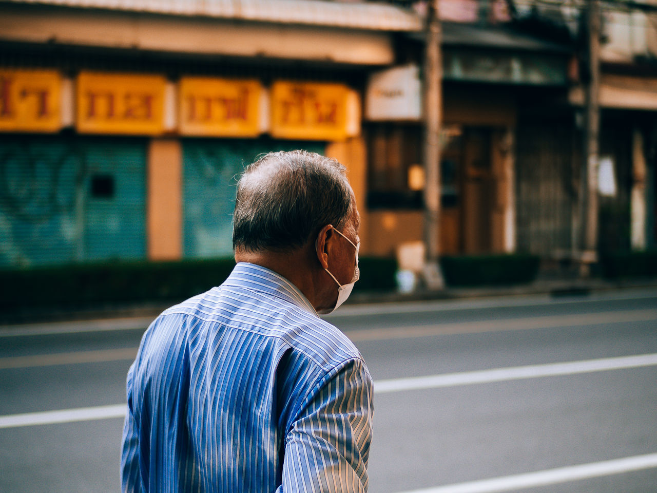 REAR VIEW OF MAN STANDING BY STREET