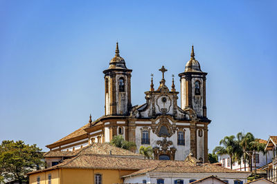 Baroque style historic church tower emerging from behind old houses in ouro preto city, minas gerais