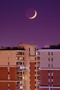 Always somewhere - crescent moon in purple sky over buildings