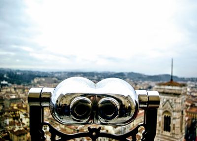 Close-up of coin-operated binoculars against cityscape