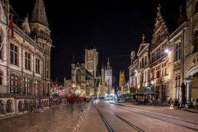 Illuminated street amidst buildings in city at night