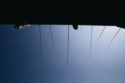 Low angle view of fishing rods against blue sky