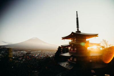 Temple by building against sky during sunset