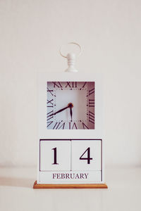 Close-up of clock on table against wall