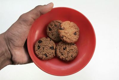 Cropped hand of person holding chocolate chip over table