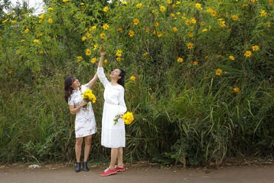 Full length of a woman standing with yellow flowers