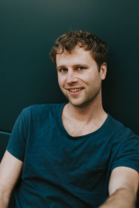 Portrait of smiling young man against black background