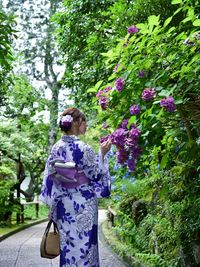 Rear view of woman standing on purple flowering plants