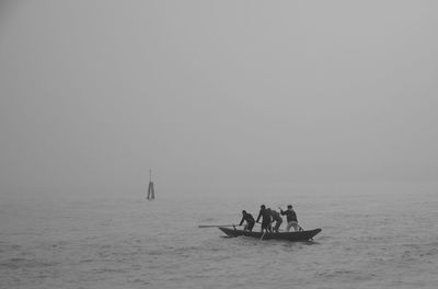People in boat sailing on sea against clear sky