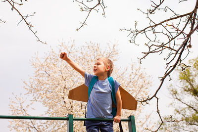 Full length of boy standing by tree against sky