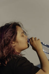 Asian girl with purple drinks water from a plastic bottle. generation z. the concept of thirst