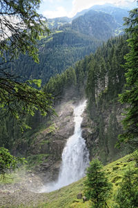 Scenic view of krimml waterfalls on rocky mountain by trees in forest