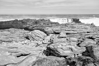 Rock formation on shore against sky