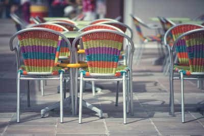 Empty chairs and tables at sidewalk cafe