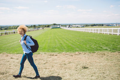 Portrait of young woman standing on field against sky