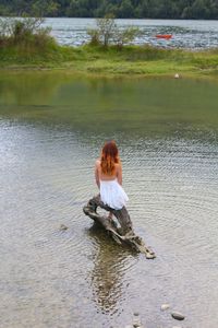 High angle view of woman sitting on driftwood