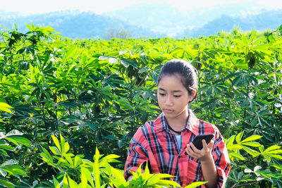 Portrait of young woman holding smart phone in farm