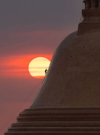 Man standing on staircase against sky during sunset