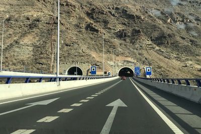 View of road sign on road against rock formation