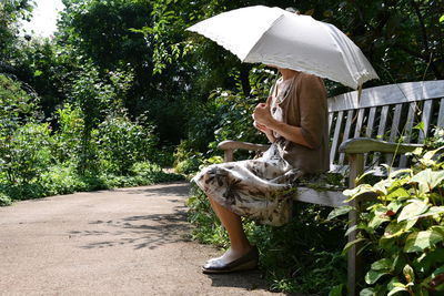 Woman with umbrella against trees