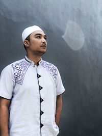 Portrait of young man looking away against wall