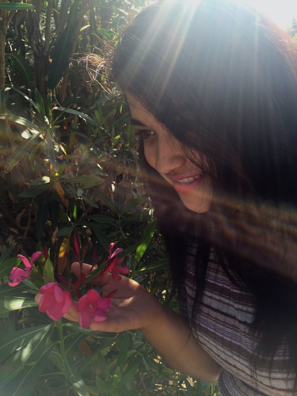 lifestyles, leisure activity, sunlight, person, flower, sunbeam, young adult, young women, headshot, lens flare, plant, holding, casual clothing, sun, day, freshness, close-up, outdoors