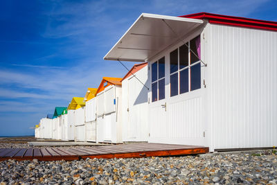 Hut on beach by buildings against sky