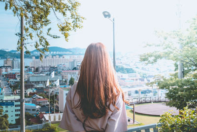 Rear view of woman against sky in city