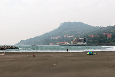 People on beach against clear sky