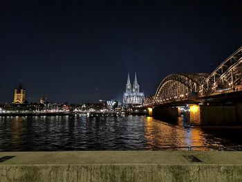 Illuminated bridge over river at night