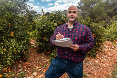 Portrait of young man standing against plants