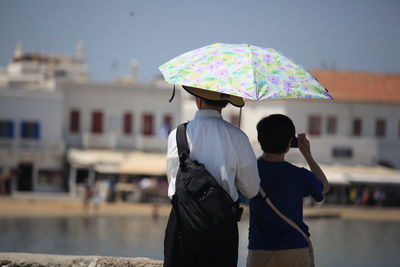 Rear view of father with son at shore during sunny day