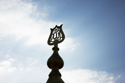 Low angle view of cross sculpture against sky