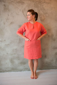 Woman in red dress standing against wall