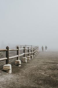 Rear view of friends walking on field during foggy weather