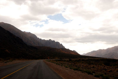 Road leading towards mountains against sky