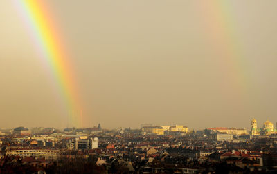 Aerial view of rainbow over buildings in city against sky