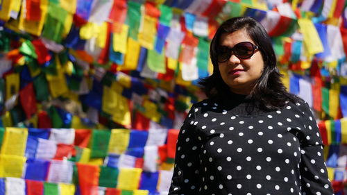 Woman wearing sunglasses standing against colorful prayer flags