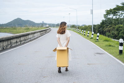 Rear view of woman walking on road