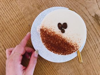 Directly above shot of hand holding coffee cup on table