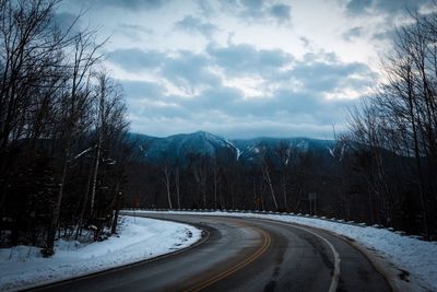 Road amidst trees against sky during winter