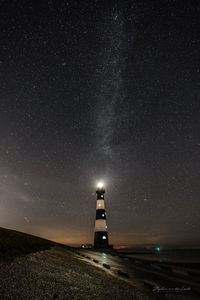 Illuminated lighthouse against sky at night