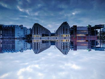 Digital composite image of buildings against cloudy sky