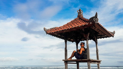 Portrait of woman sitting by sea against sky