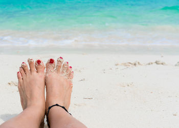 Low section of woman relaxing on sand at beach