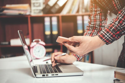 Midsection of man using mobile phone on table