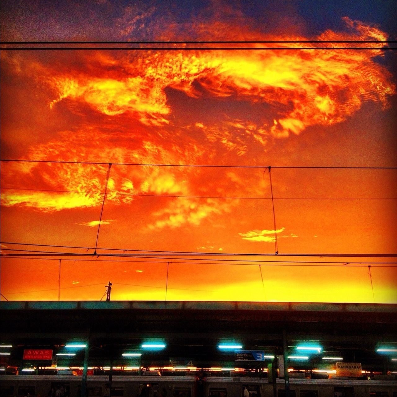 illuminated, low angle view, sunset, sky, street light, architecture, built structure, building exterior, orange color, lighting equipment, power line, transportation, silhouette, cloud - sky, electricity, dusk, cable, city, no people, outdoors