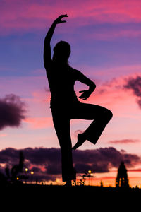 Silhouette woman standing on field against sky during sunset